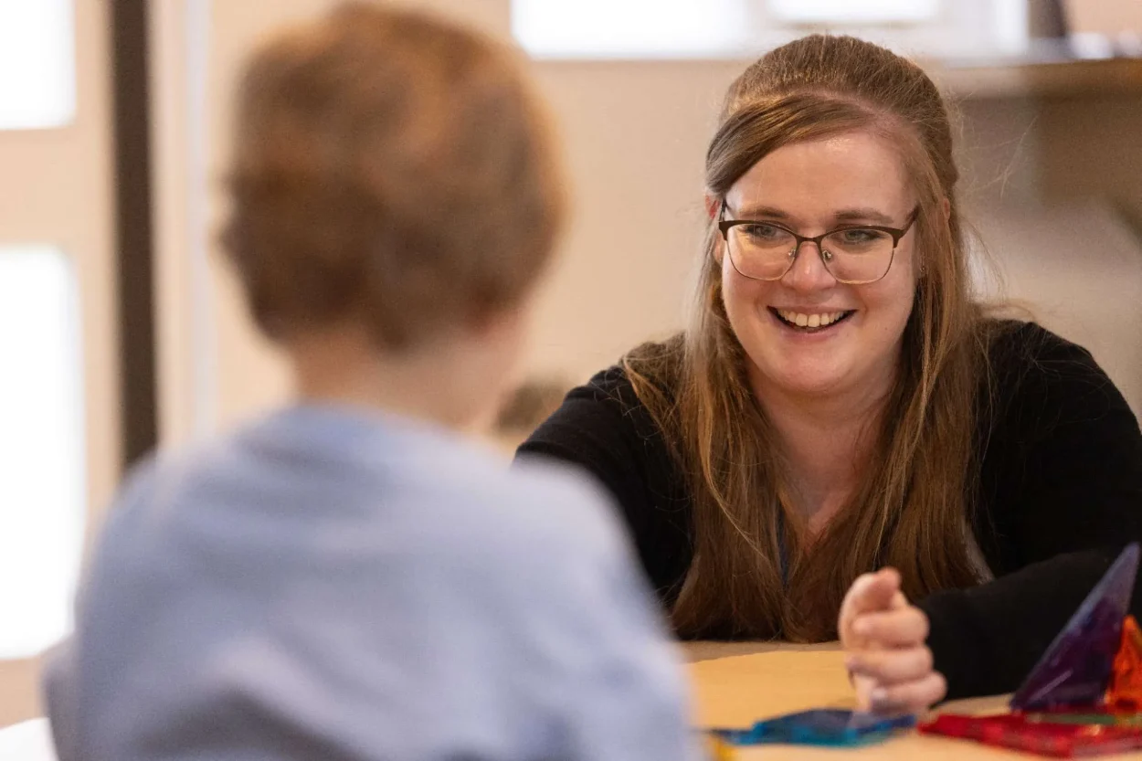 A nursery practitioner smiling with a child during one-to-one play