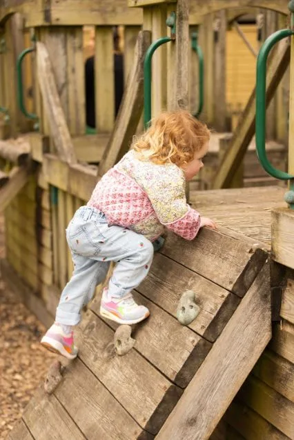 A nursery child climbing and exploring outdoors at Clayesmore Nursery