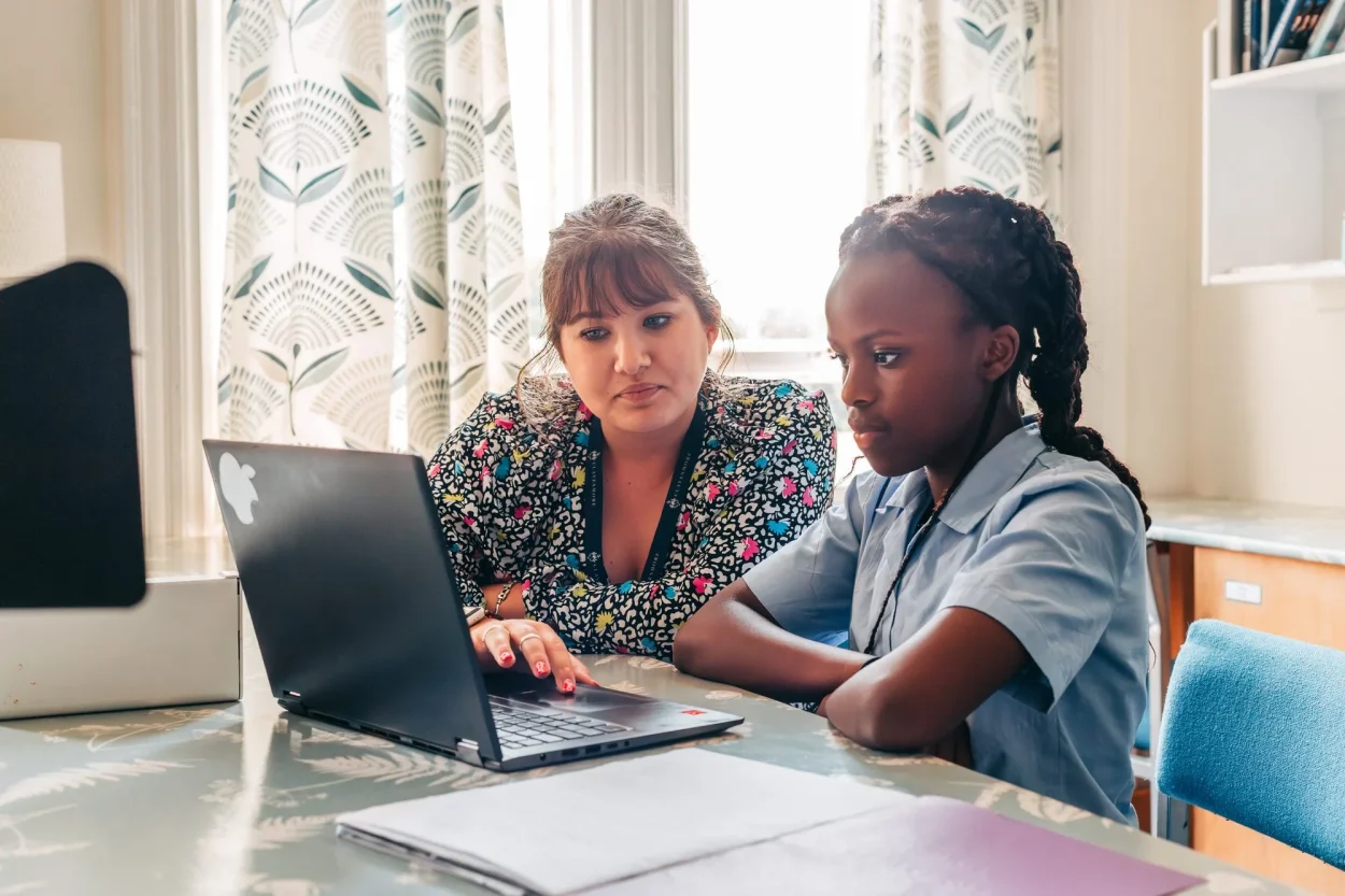 A pupil working with a teacher at a laptop